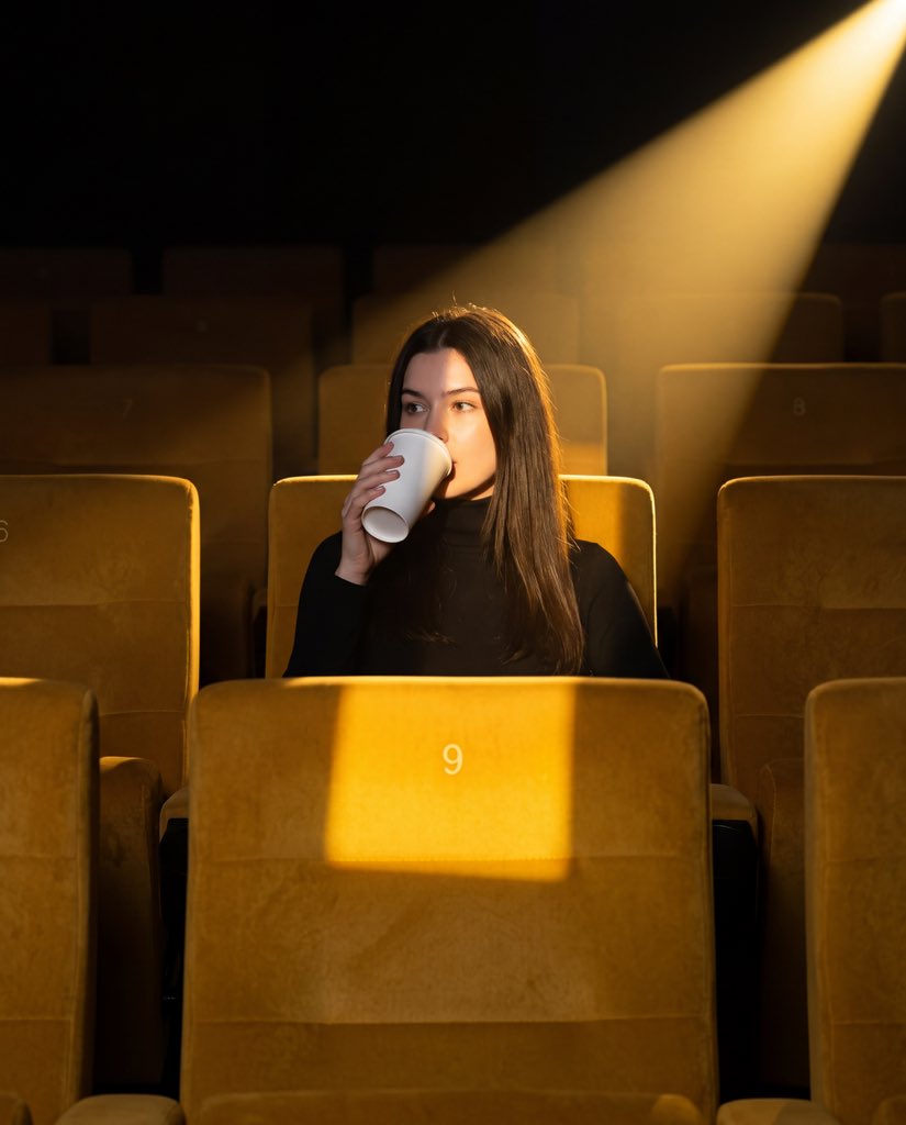 나노바나나 사람: 비어 있는 영화관에서 흰 컵을 들고 마시는 장면 AI image prompt example